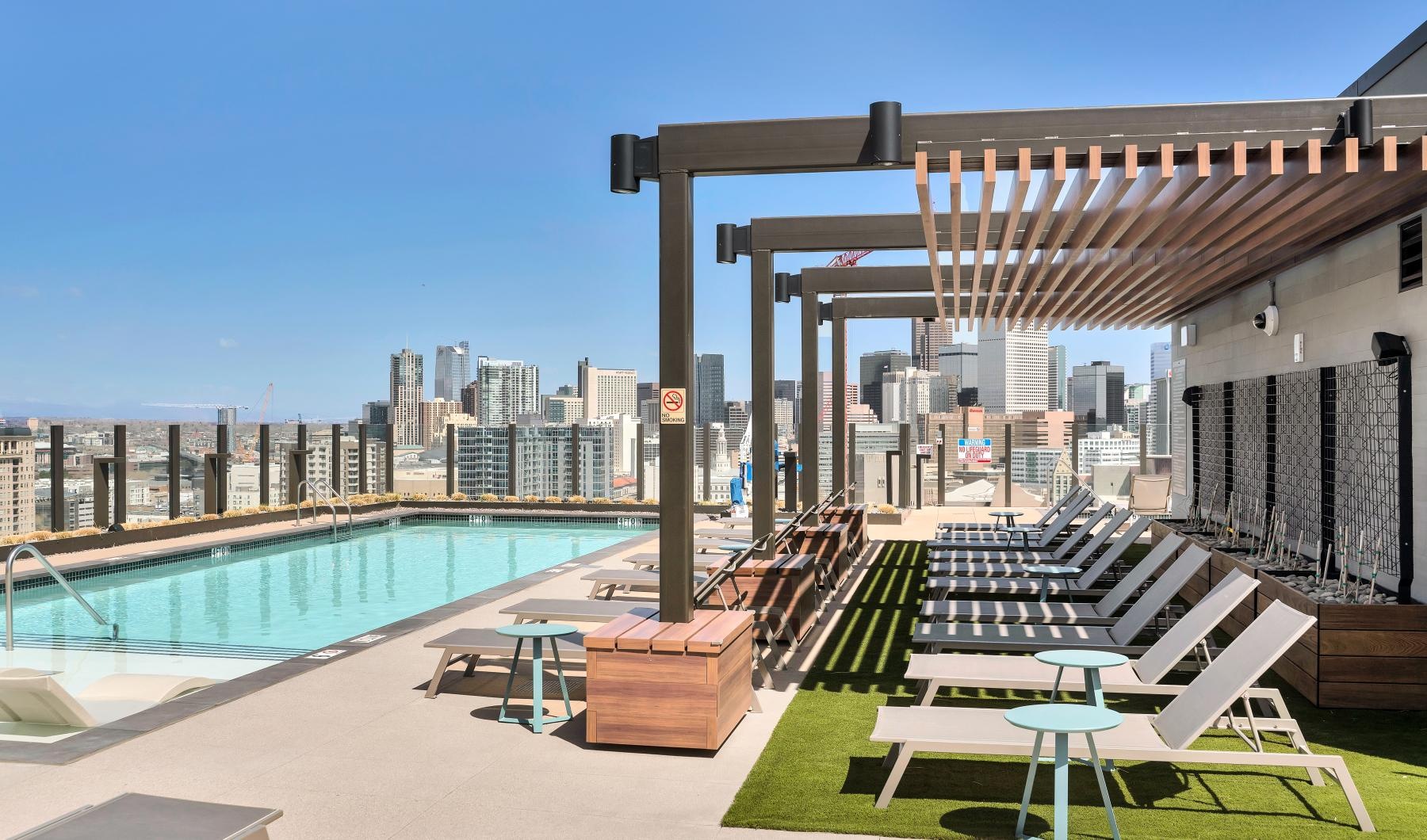Resort-style swimming pool a pool with lounge chairs and a view of a city