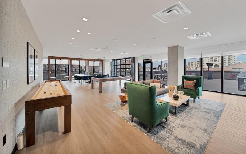 a large room with a shuffleboard table chairs and large windows